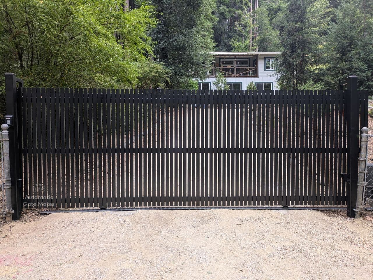 Black vertical slat privacy gate for forest driveway installed by Automatic Gate Mates in Bay Area