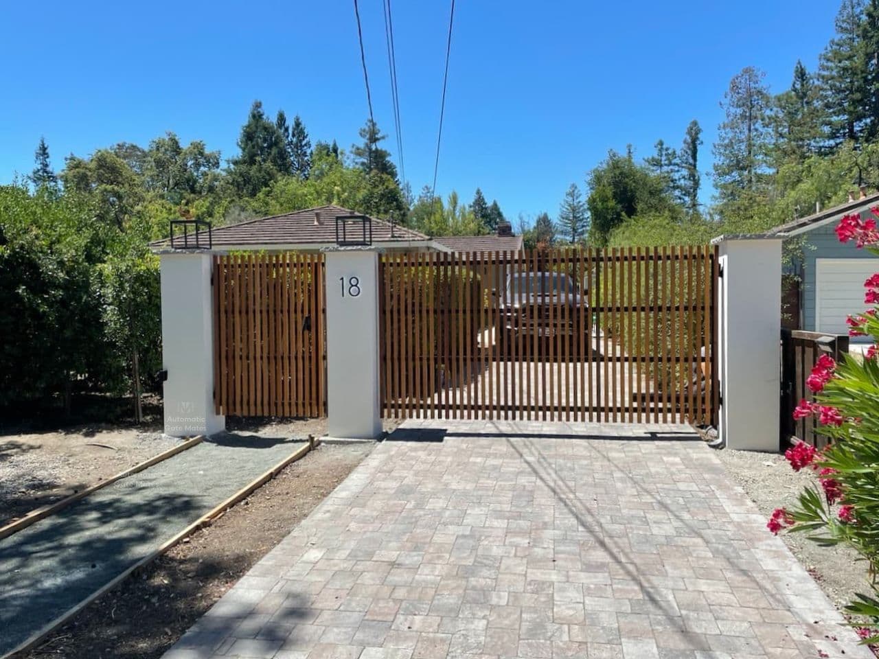 Custom wood and steel driveway gate with stone accent wall installed by Automatic Gate Mates in Bay Area