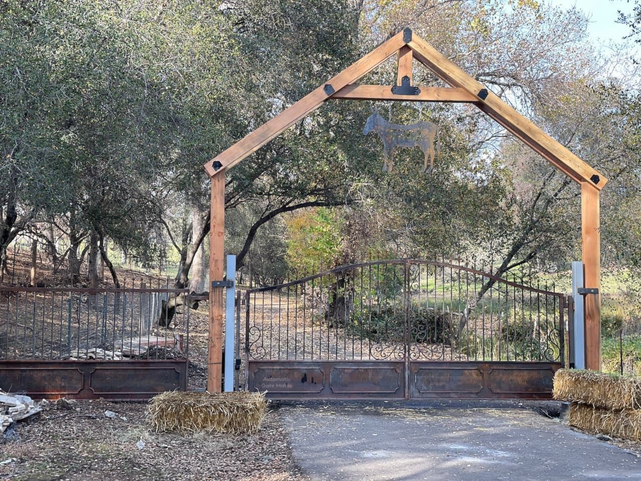 Custom wrought iron ranch gate with wooden frame and animal design installed by Automatic Gate Mates in Bay Area